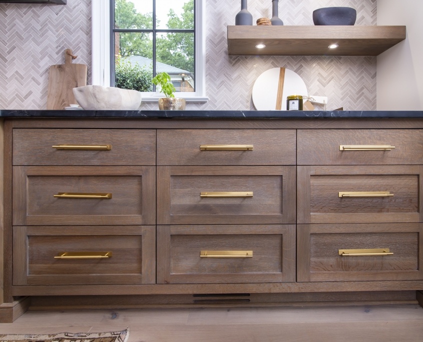 white oak kitchen cabinet drawers with brass hardware and black countertop