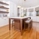 walnut kitchen island with bar stools in white kitchen with floating shelves