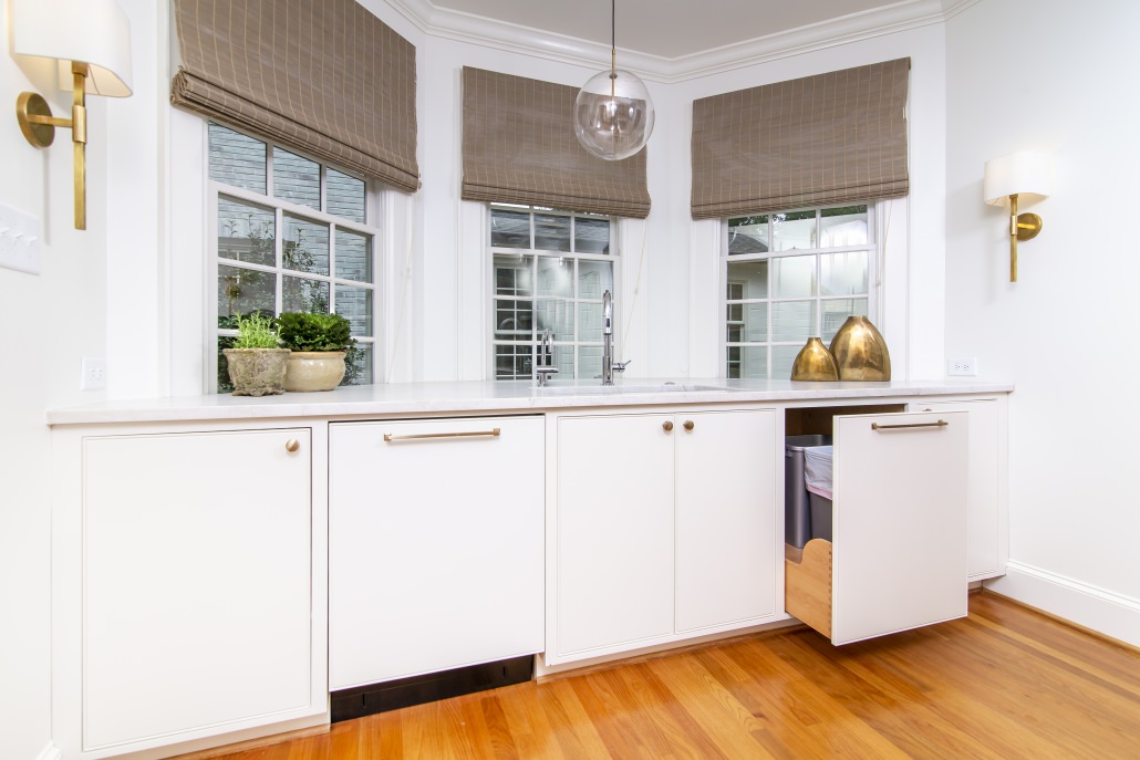 Bay window with white kitchen cabinets and trash can pull-out