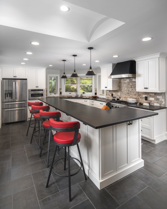 modern white kitchen with black countertops and red bar stool chairs