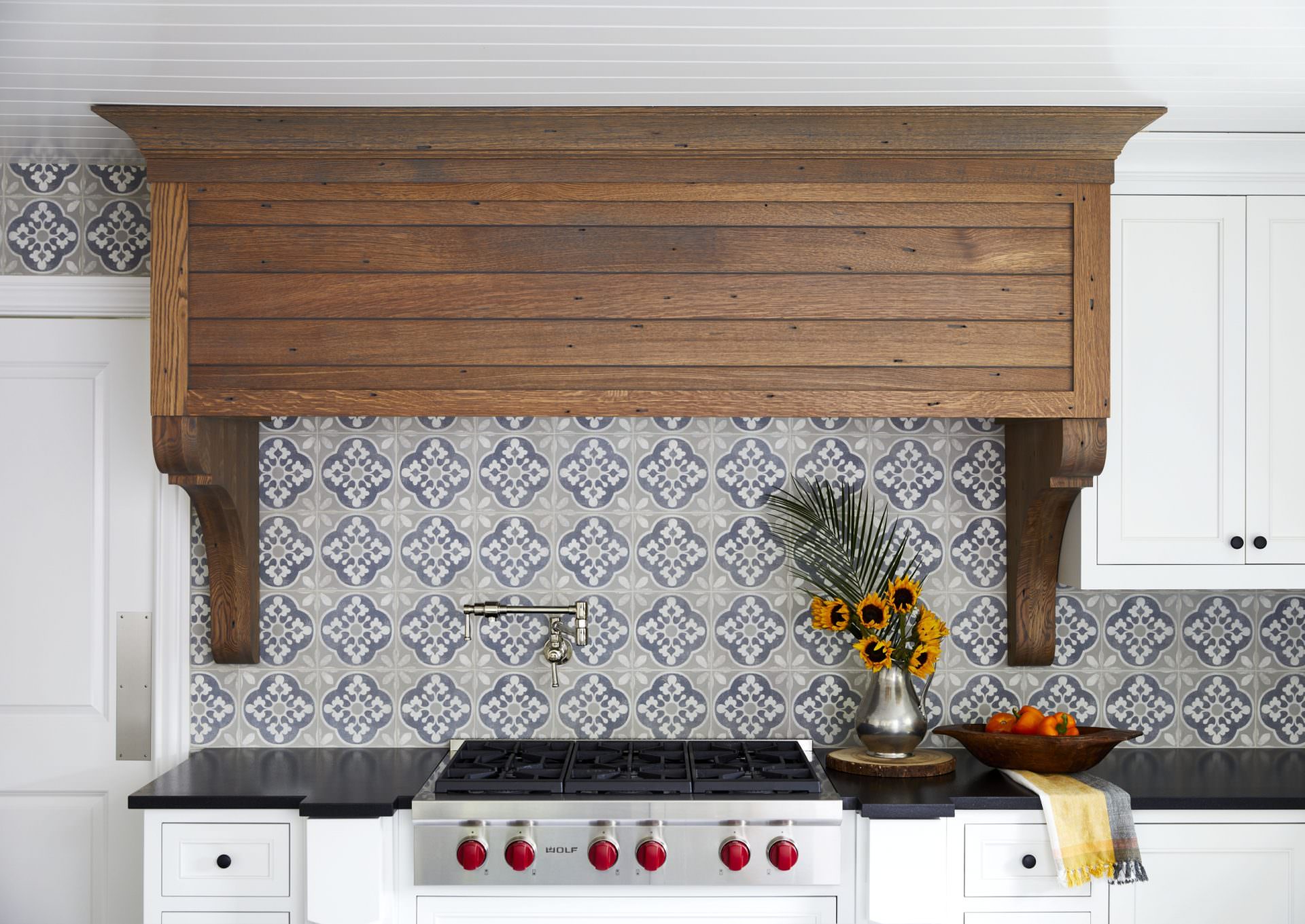 custom range wood hood from quarter sawn white oak and surrounded by white kitchen cabinets and tile backsplash