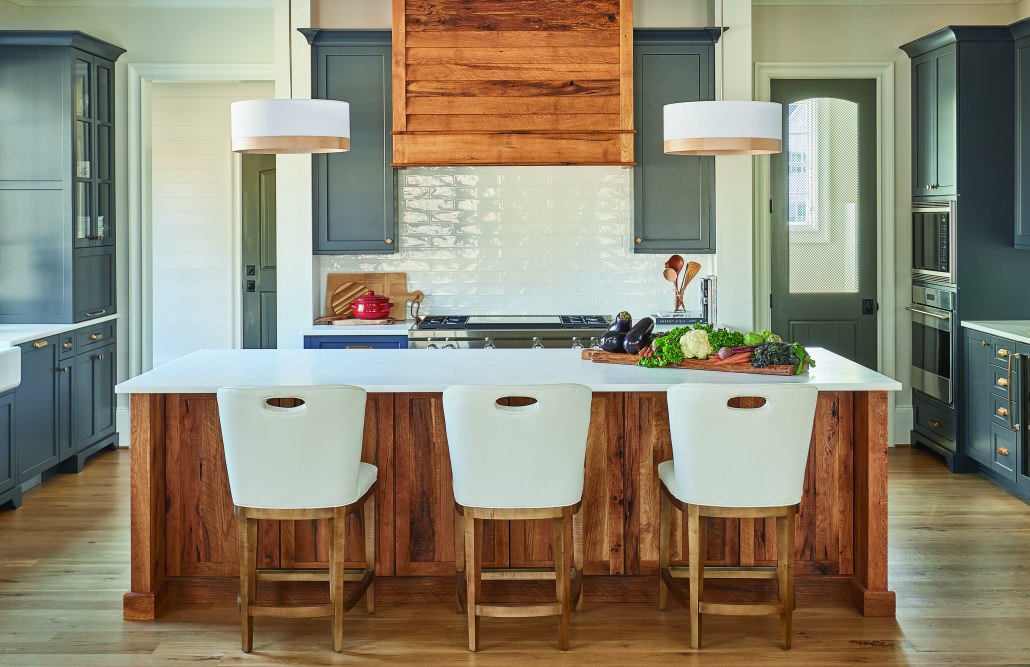 modern farmhouse kitchen with reclaimed wood kitchen island look and matching range hood surrounded by blue gray cabinets and three white bar stools