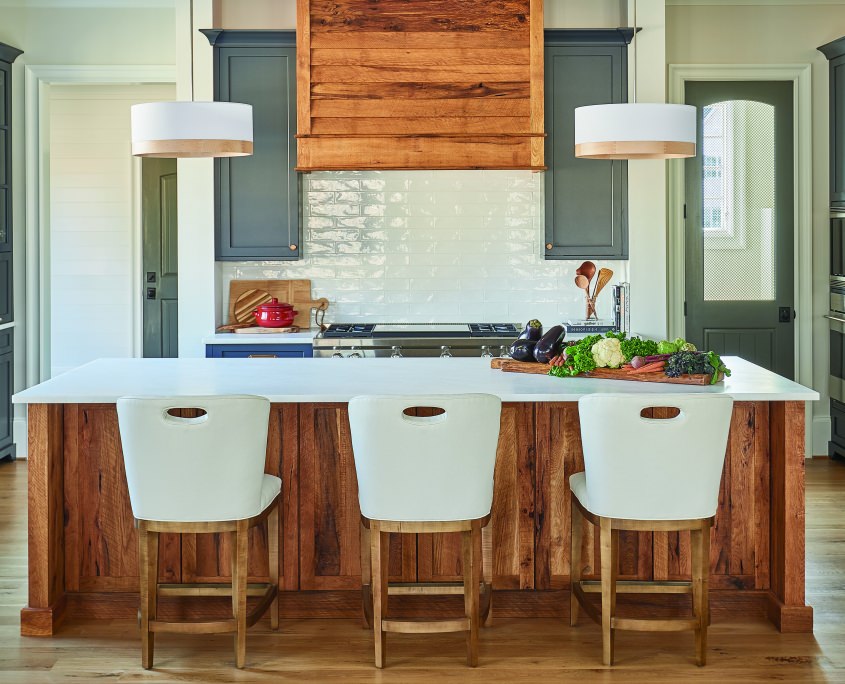 modern farmhouse kitchen with reclaimed wood kitchen island look and matching range hood surrounded by blue gray cabinets and three white bar stools