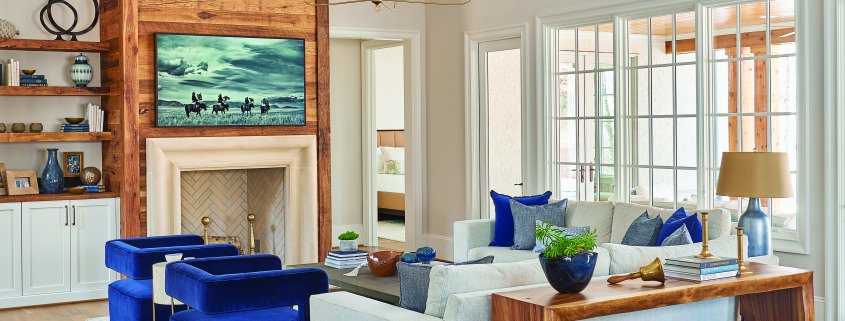 rustic modern family room with vaulted ceilings, floating shelves, white cabinets and blue chairs