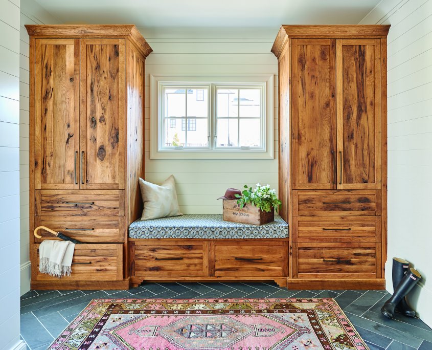Farmhouse mudroom with wood bench seating and two large storage cabinets with drawers