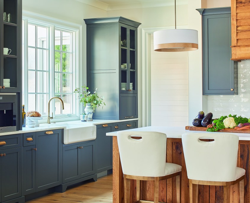 modern farmhouse kitchen with apron sink and reclaimed wood kitchen island and large window framed by large blue gray cabinets