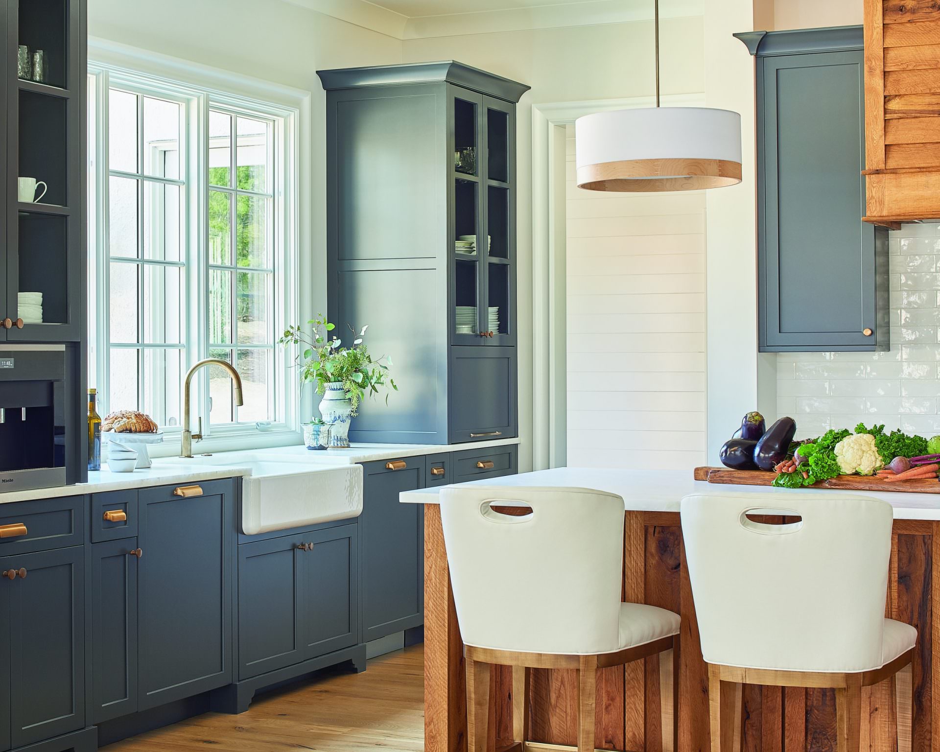 modern farmhouse kitchen with apron sink and reclaimed wood kitchen island and large window framed by large blue gray cabinets
